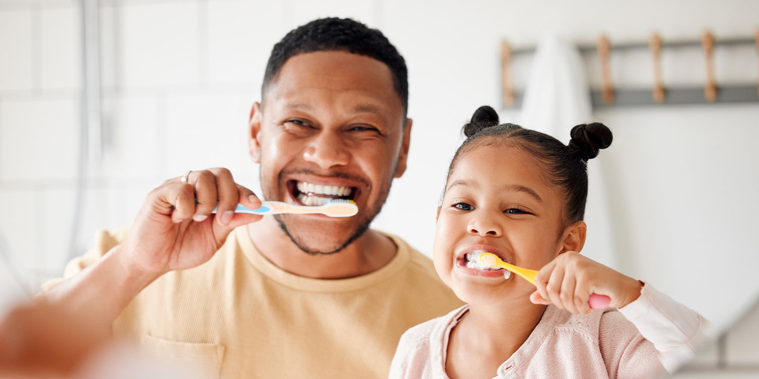 father and daughter brushing teeth side by side